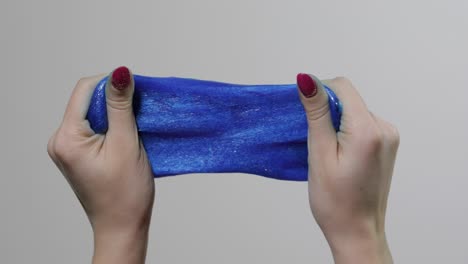 Woman-hands-playing-with-oddly-satisfying-blue-slime-gooey-substance.-Antistress