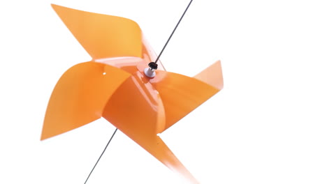 orange color plastic pinwheel rotates with blowing wind