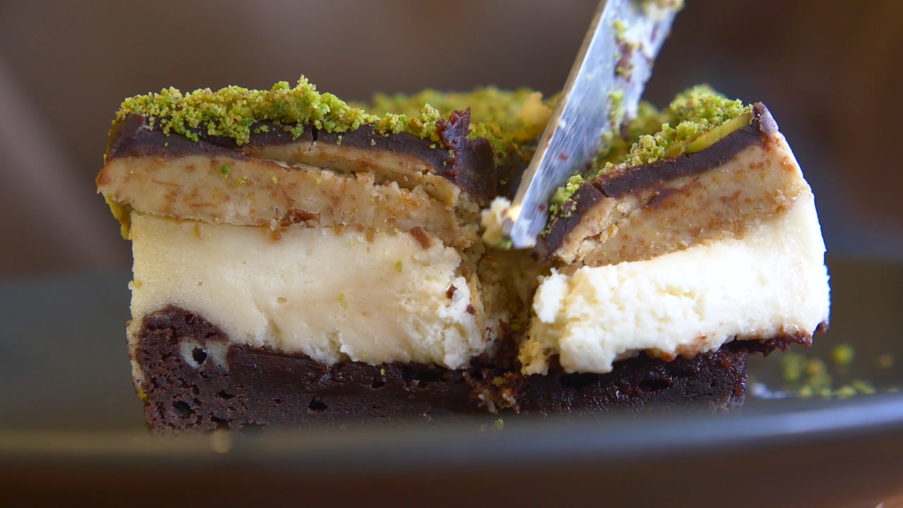Cutting a Slice of Layered Chocolate Pistachio Dessert