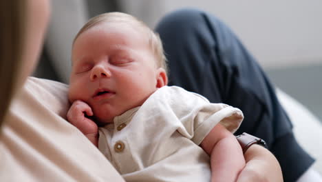 sweet newborn baby holding a hand near the cheek while sleeping. infant resting in mom's hands. close up.