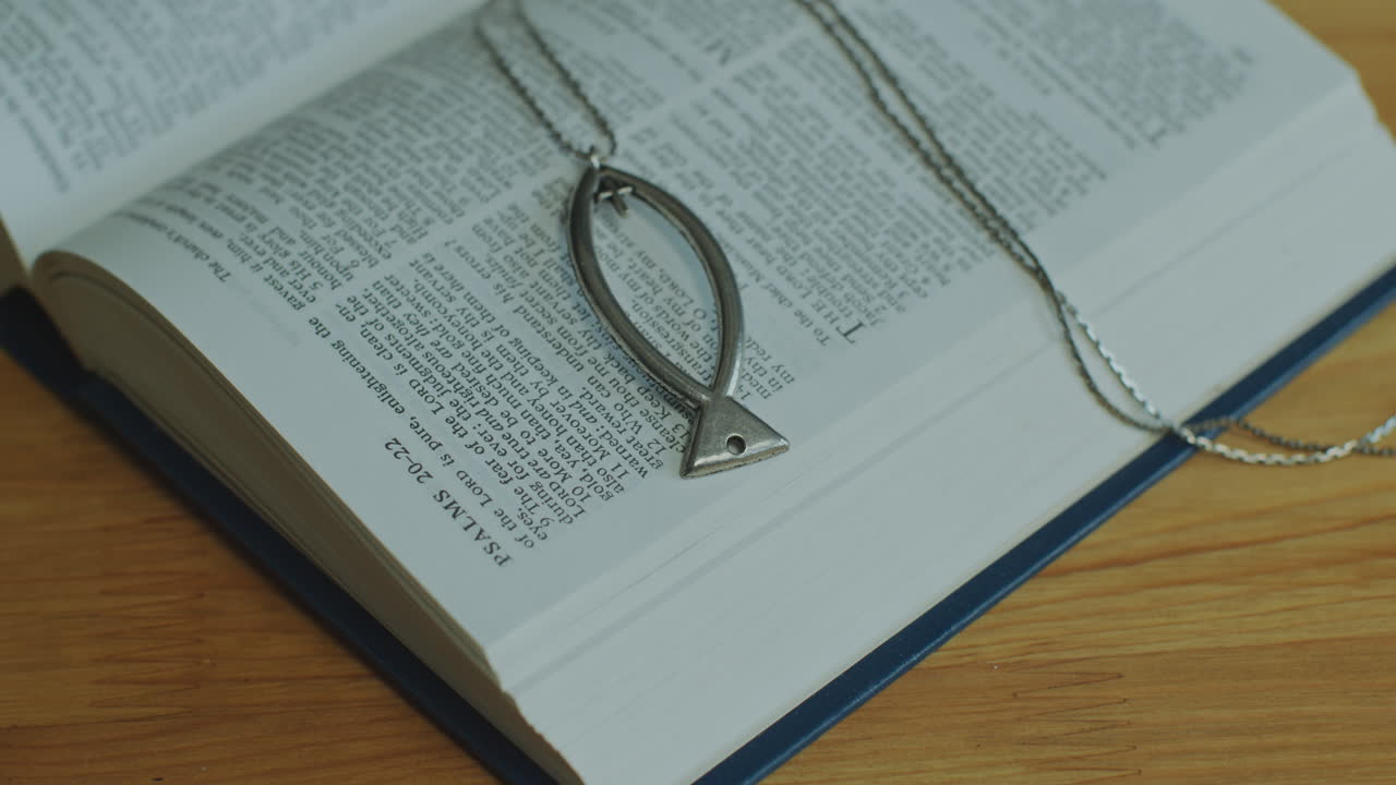 Close-Up of Opened Bible Book with Psalms Text and Ichthus Necklace