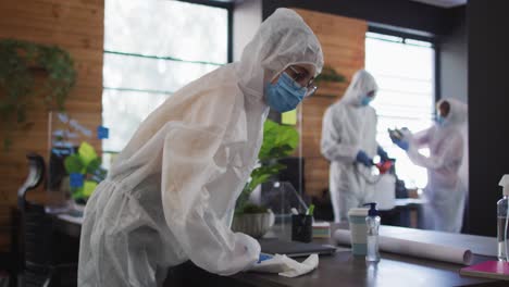 equipo de trabajadores de la salud con ropa de protección limpiando la oficina con un pulverizador de desinfectante