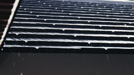 rain is trickling down from the eaves and roof tiles of a house