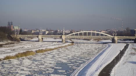 Río-Congelado-Con-Témpanos-De-Hielo-Con-Un-Puente-Y-La-Ciudad-Al-Fondo-1