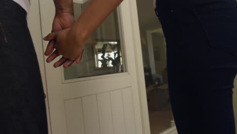 pareja de raza mixta tomados de la mano en su casa