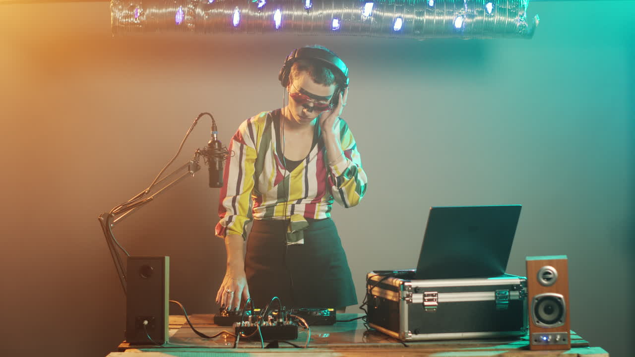 여성 디스크 조키가 서에서 테크노 음악을 제작하고 있습니다.