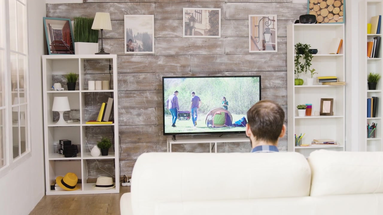 Uomo seduto sul divano che guarda la televisione nel soggiorno