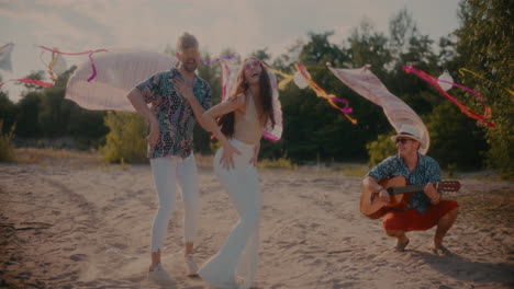 Happy-young-couple-dancing-bachata-by-friend-playing-guitar