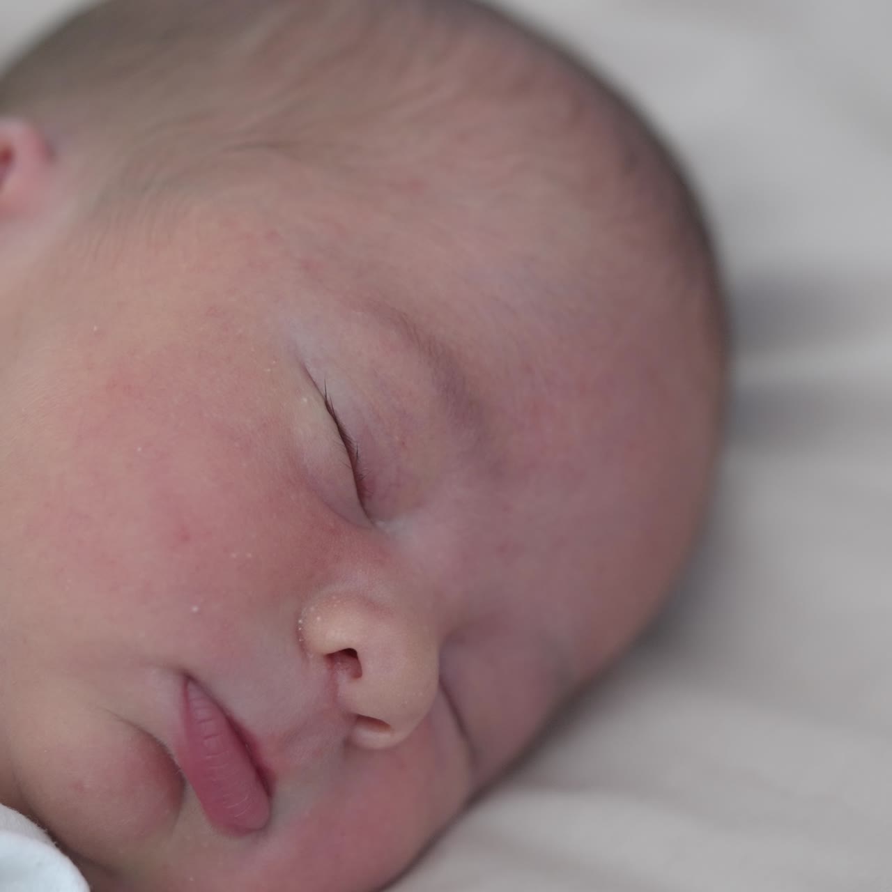 Adorable infant sleeps calm on soft bed at home. Facial portrait of a baby boy sleeping. Healthy dream. Quiet night for parents after childbirth
