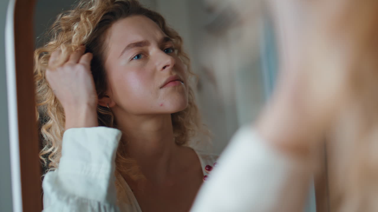 Primo piano di donna che si guarda allo specchio del bagno a casa. Ragazza preoccupata che si tocca la pelle del viso.
