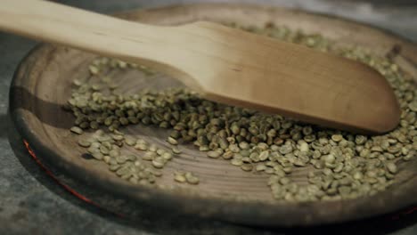 Aufnahmen-Eines-Paddels,-Das-Grüne-Kaffeebohnen-Auf-Einem-Heißen-Stein-Auf-Einem-Ofen-Bewegt