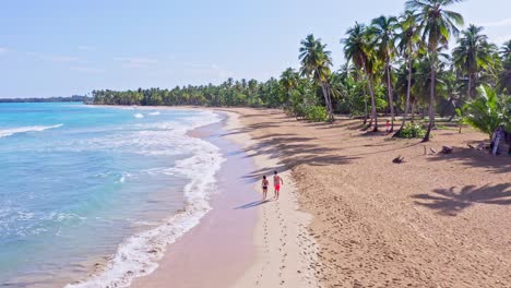 honeymoon couple in swimwear walks on secluded caribbean beach