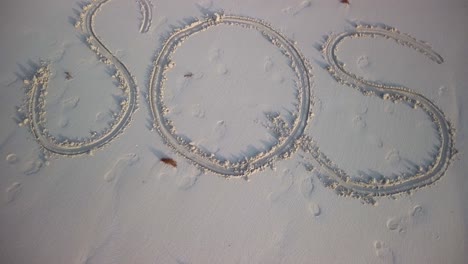 Drehschuss-Von-Sos,-Geschrieben-Im-Sand-An-Einem-Strand