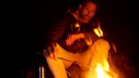 man cooking food on campfire in the forest 4k