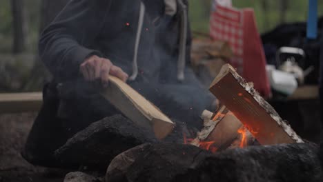 man putting more wood in forest fire slow motion fire