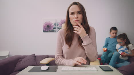 Business-mother-face-looking-at-monitor-with-kids-playing-on-background