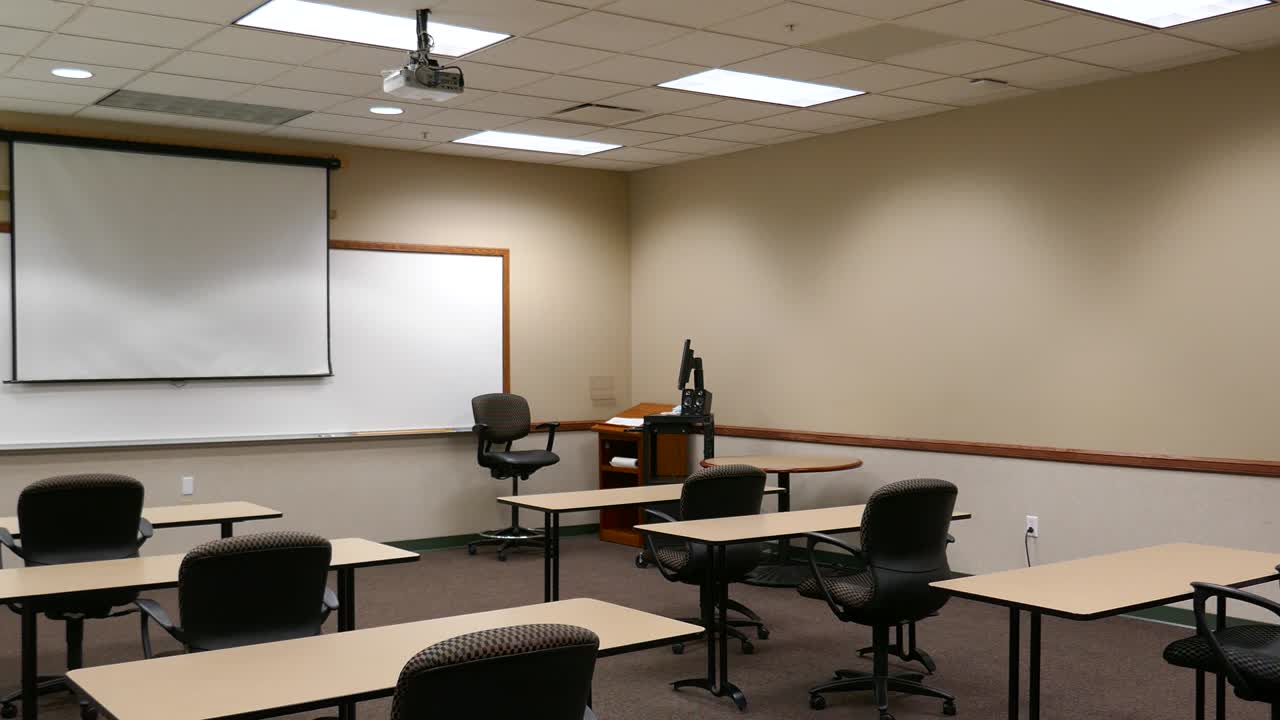 Aula con sedie vuote, computer e schermo di proiezione frontale
