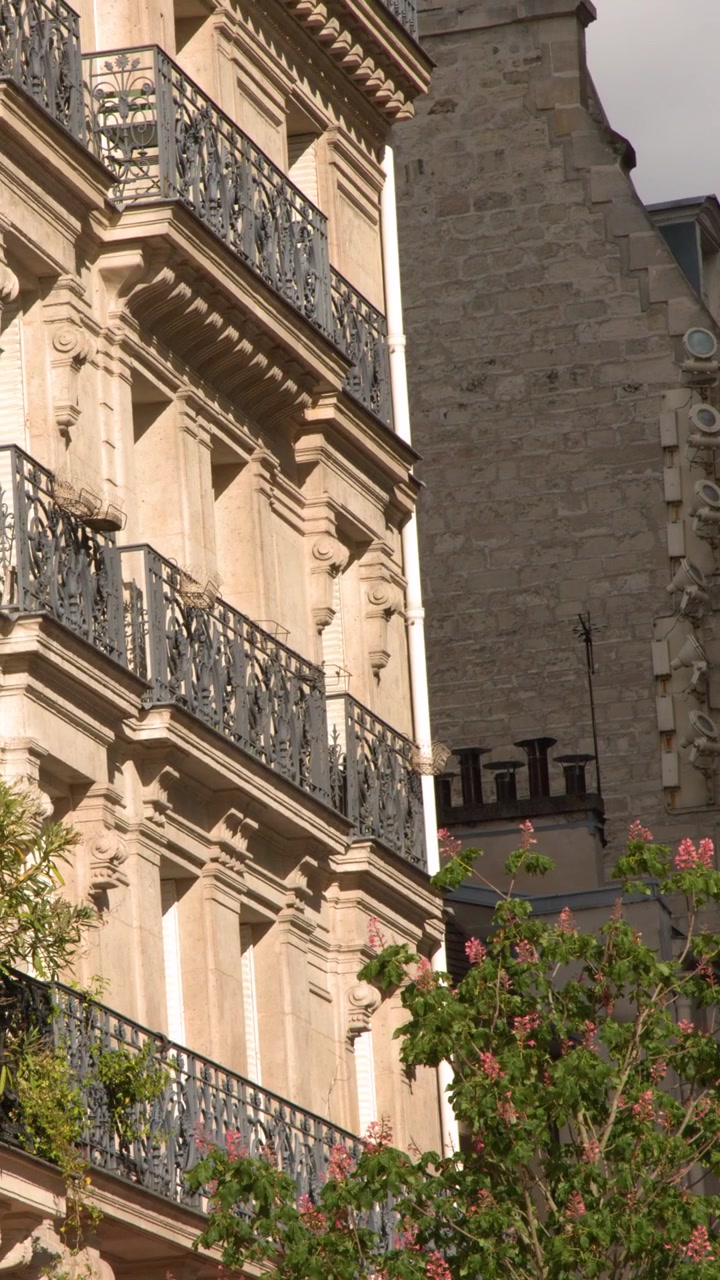 Inquadratura dal basso che rivela facciate ornate di appartamenti haussmanniani e balconi in ferro battuto a Parigi, Francia.