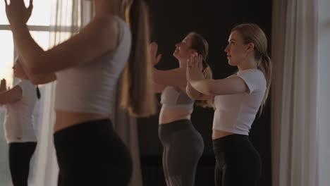 A-group-of-women-is-engaged-in-stretching-and-balance-with-an-instructor-in-a-beautiful-hall-with-large-windows.-Healthy-lifestyle-group-classes.-Women's-sports-club-slow-motion