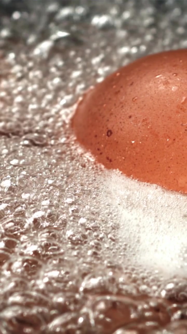 Close-up of a Brown Egg Boiling in Hot Water