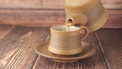Verter el té de una tetera en una taza
