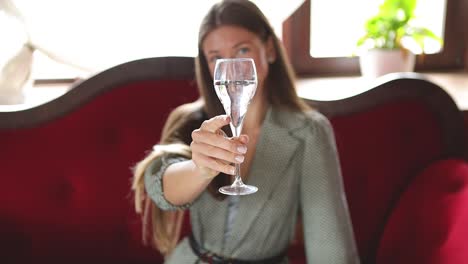 young attractive caucasian female model lifting a glass of champagne, giving a toast and drinking it