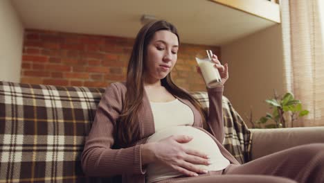 pregnant woman drinking milk at home