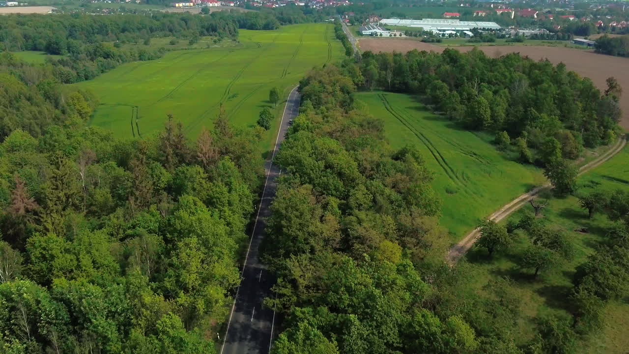 시골 지역의 들판과 숲 사이의 도로에서 운전하는 자동차의 공중 전망