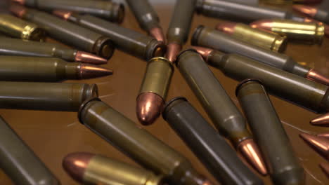 slider close up of ar-15 and 9mm gun ammo laying on a glass table