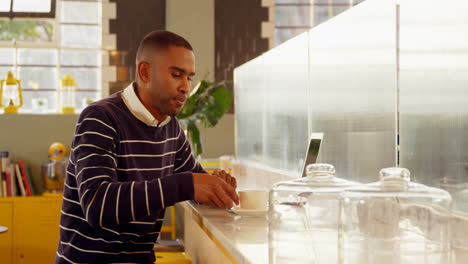 Male-executive-having-coffee-while-using-laptop-in-cafeteria-4k