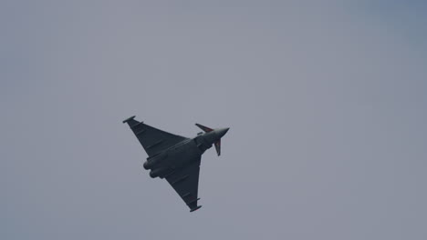 military jet fighter with special tail art flying at an airshow during aerial maneuver