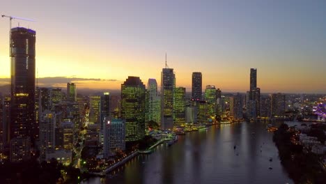 Rising-aerial-view-of-a-Brisbane-city-riverside-at-sunset