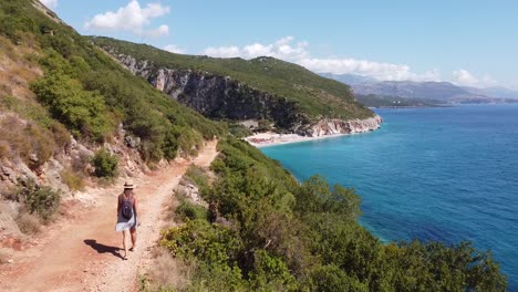 Chica-Caminando-A-La-Playa-Y-Al-Cañón-De-Gjipe-En-Dhermi,-Albania---Vista-Aérea-De-Drones