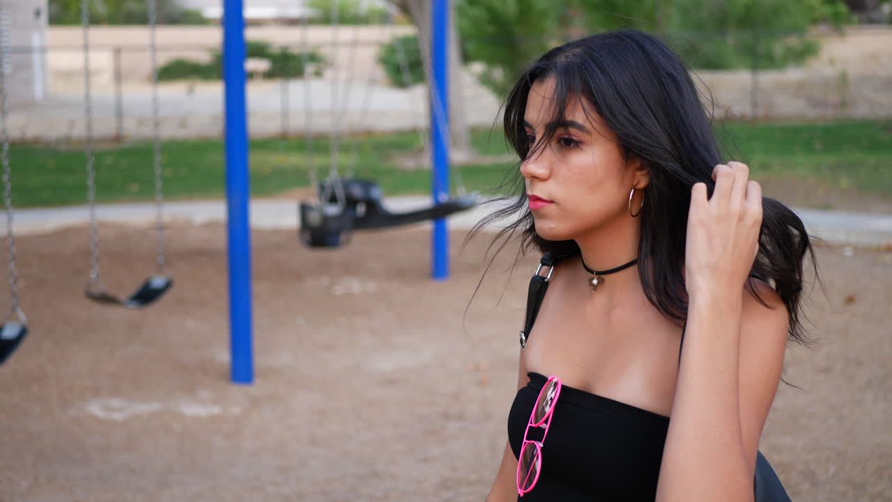 A beautiful young woman model wearing vintage fashion clothing with retro pink aviator sunglasses in a park SLOW MOTION