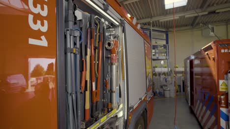 firefighter retrieving bolt cutters from the fire truck in the station