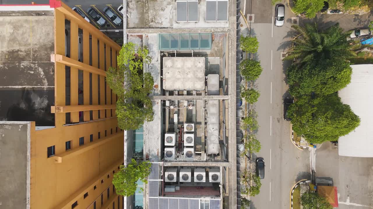 Tomada aérea de drone de cima para baixo revelando painéis solares em telhados, ruas urbanas e quadras esportivas, exibindo energia sustentável em uma paisagem urbana vibrante. Kuala Lumpur, Malásia.