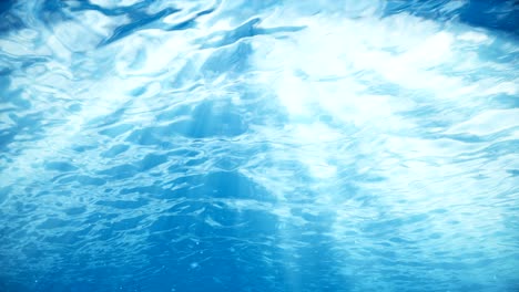 rays of sunlight shining from above penetrate deep clear blue water. sun light beams underwater. small bubbles move up, under the water surface. seamless loop-able 3d animation. 4k