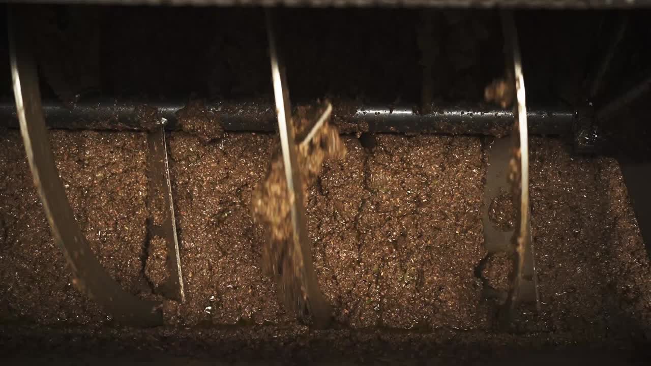 Olive paste releasing fresh oil streams inside industrial press Portugal