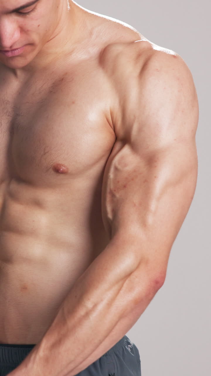 Uomo muscoloso che flette i bicipiti e il petto in studio