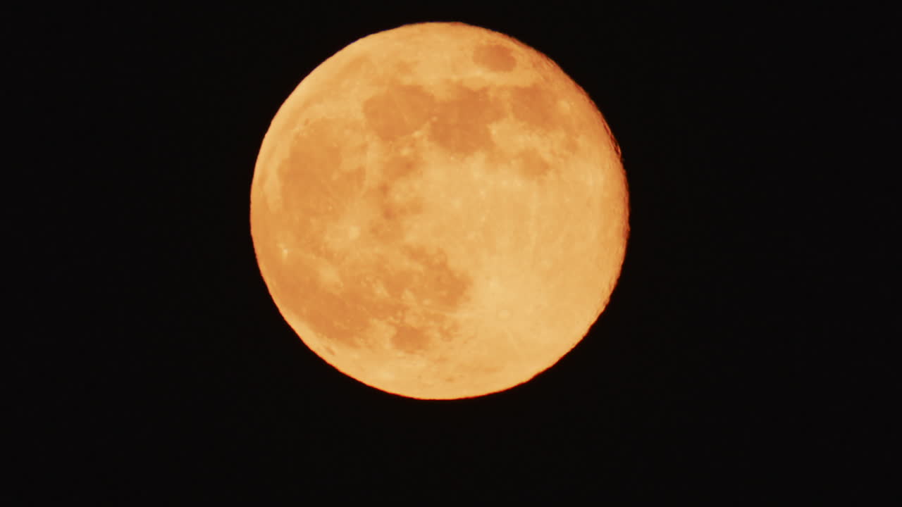 Large full moon rising against a dark night sky with clear details and dramatic atmosphere