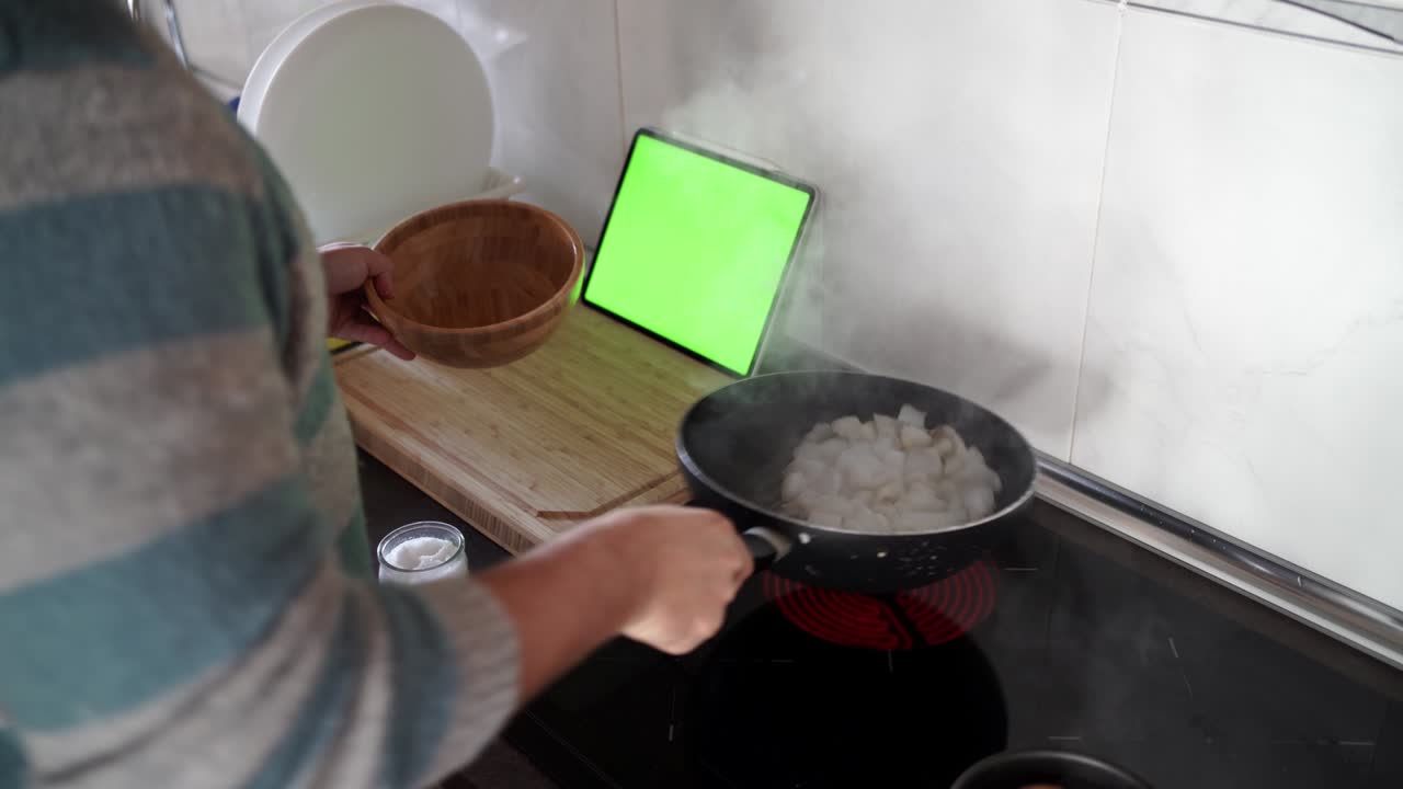 sobre el hombro de un hombre cocinando sepia usando una receta de su tableta