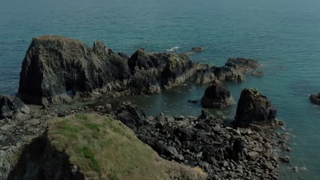 Wide-angle-aerial-drone-shot-of-rocky-cliff-near-beautiful-ocean-seaside-at-day