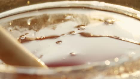 honey dripping from a wooden spoon into a glass jar