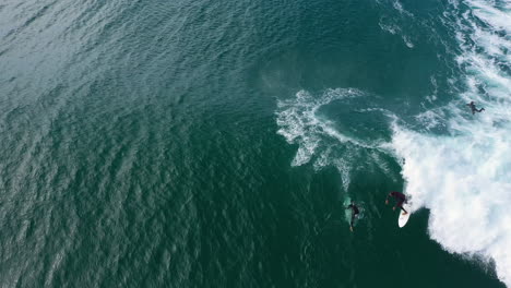 toma aérea de 4k de un surfista profesional girando y montando una gran ola azul en lennox head, australia