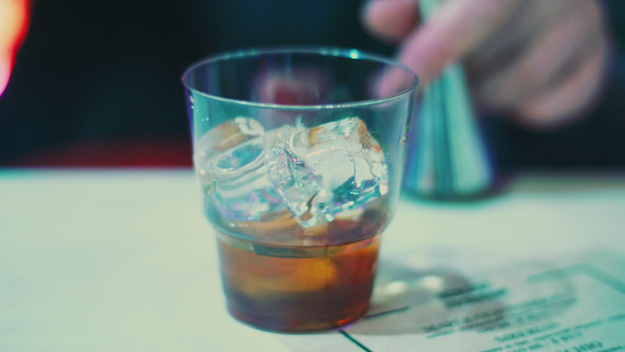 barman vertiendo bebida alcohólica en un vaso con cubitos de hielo. barman haciendo whisky