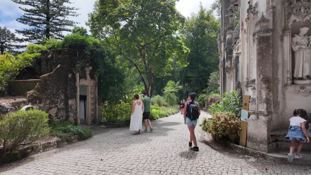 Tourists enjoy the scenic beauty of Quinta da Regaleira, Sintra, with its lush gardens and historic castle