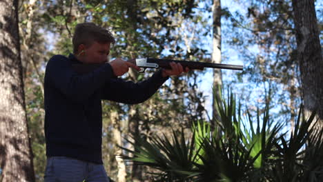 young boy aims gun at target