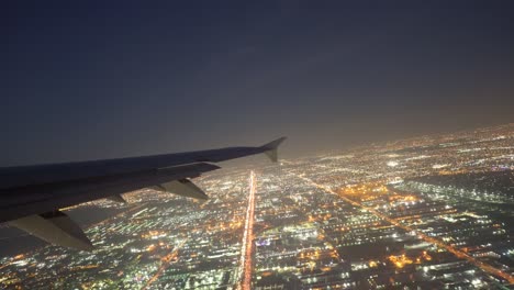 plane flying over glowing city at night on take off