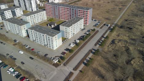 aerial drone pulling back and flying away in reverse from tall new apartment complexes in lasnamäe estonia during a sunny day in spring. camera lifts up and also reveals a large white russian church.