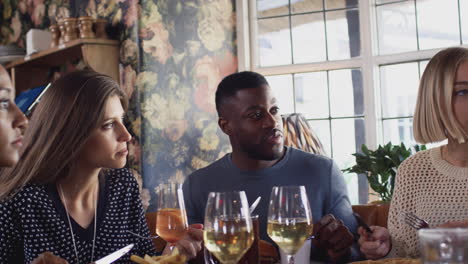 group of friends meeting for meal in traditional english pub